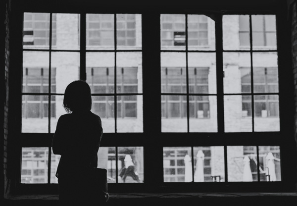 Person standing by two large windows looking outside